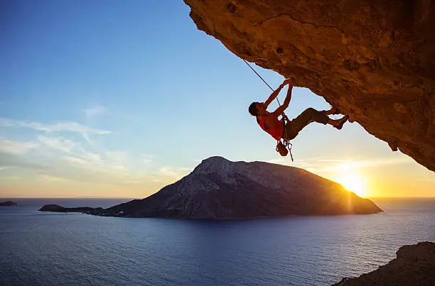 Male climber on overhanging rock at sunset