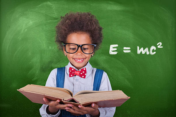 istock Schoolboy reading a book in front of school board 623781638