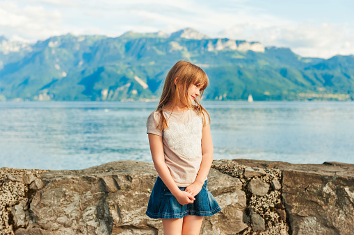 Adorable little girl resting by the lake on a nice warm summer day