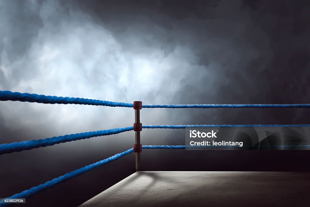 View of a regular boxing ring surrounded by blue ropes View of a regular boxing ring surrounded by blue ropes spotlit by a spotlight Boxing Ring Stock Photo