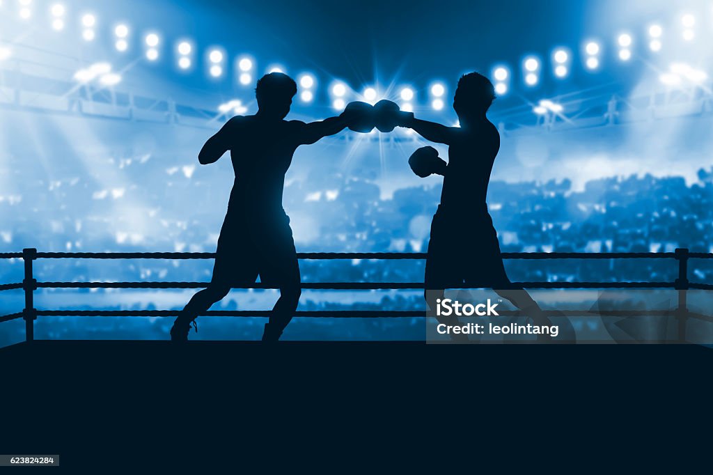 Silhouette of two professional asian boxer fight in the boxing Silhouette of two professional asian boxer fight in the boxing match against stadium spotlight Boxing - Sport Stock Photo