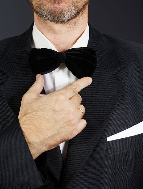 istock Bearded man wearing black bow tie and suit against dark 623825672