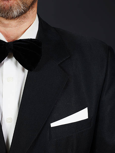 istock Bearded man wearing black suit and bow tie against dark 623825816