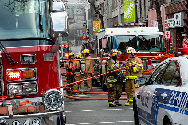 Montreal Firefighters on Street at Historic Heritage Building Fire Montreal, Сanada - November 17, 2016: Montreal Firefighters and Police in action on the scene of a major fire in China Town. Scene on the street in Montreal where North America's first movie theatre, a Heritage Building and Historic site burns to the ground with fire trucks, police and firemen working to put out the fire. police and firemen stock pictures, royalty-free photos & images