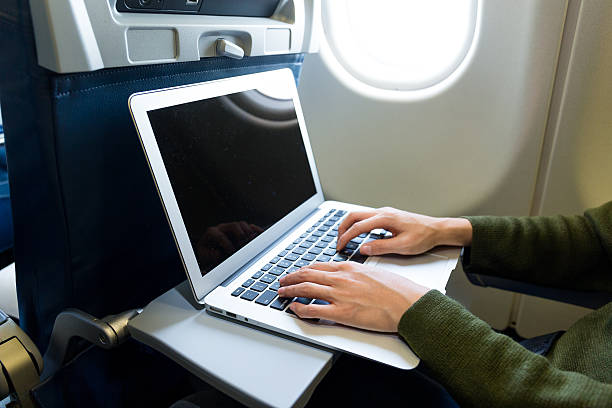 飛行機のラップトップコンピュータを使用している女性 - airplane seat ストックフォトと画像