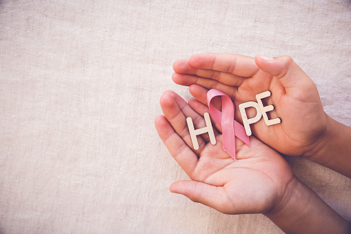 Cinta rosa y hope palabra en las manos, conciencia del cáncer de mama photo