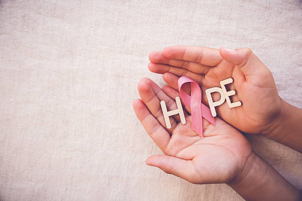 ruban rose et mot espoir sur les mains, sensibilisation au cancer du sein - octobre rose photos et images de collection