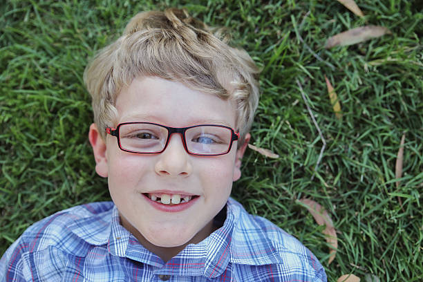 istock Happy little boy wearing glasses laying on grass 623828324