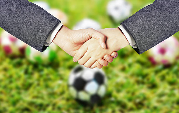 istock business man hand shake with soccer blur background 623846560