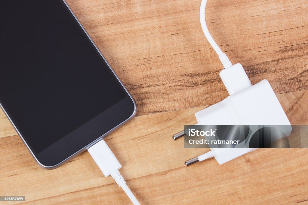 Mobiltelefon mit angeschlossenem Stecker des Ladegeräts, Smartphone-Ladefunktion - Lizenzfrei Adapter Stock-Foto