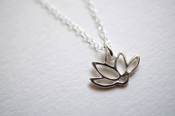 srebrny naszyjnik z kwiatów lotosu na białym tle z bliska - charm necklace zdjęcia i obrazy z banku zdjęć