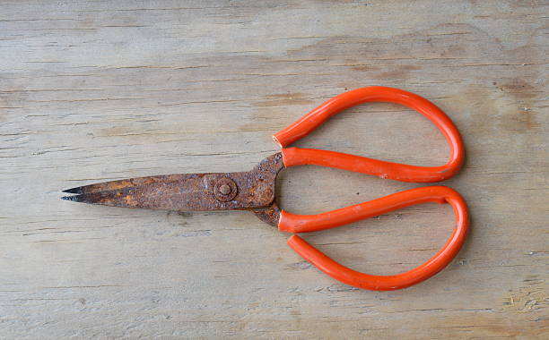 istock old rusty scissor with red plastic handle on wooden board 623858984