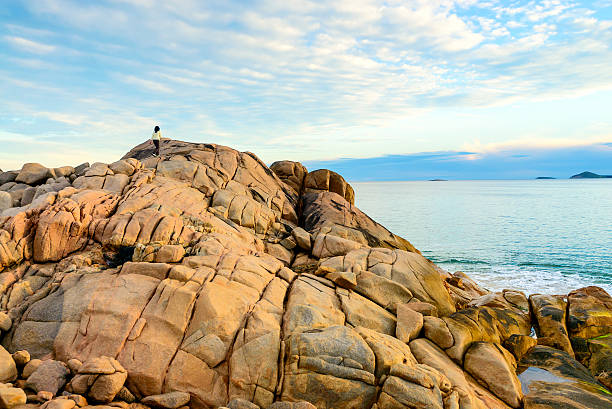 Woman climbing to top of the rock at Port Elliot, South Australia