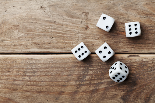 White dice on wooden table top view. Gambling devices. Game of chance concept.