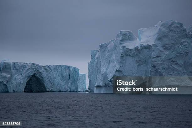 Two Large Icebergs With Small Cave Stock Photo - Download Image Now - Cave, Iceberg - Ice Formation, Arctic