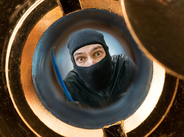 istock View through peephole. Robber masked with balaclava behind door 623869296