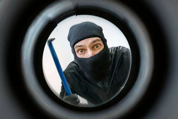 View through peephole. Thief masked with balaclava is behind door.