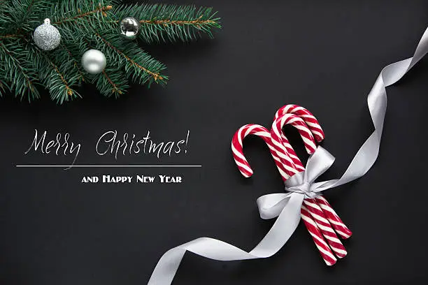 Christmas or New Year decoration background. Fir tree branches, candy on black background with copy space. Top view. Pattern.