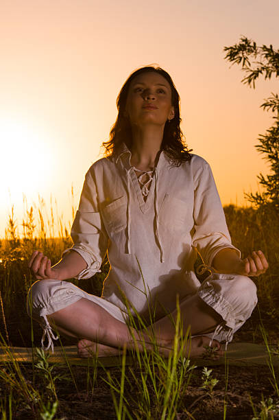 Beautiful Yoga woman siting against sunrise