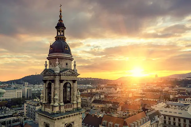 Aerial cityscape of Budapest with landmarks buildings including Gellert Hill with Citadella, Castle Hill and St Stephen's Basilica at sunset.