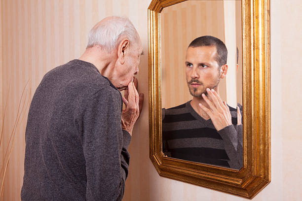 hombre mayor mirándose a un joven en el espejo - one senior man only fotografías e imágenes de stock