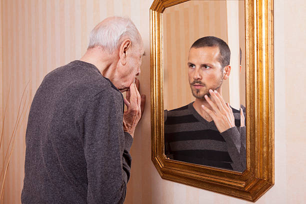 vieil homme regardant un jeune lui-même dans le miroir - utopie photos et images de collection