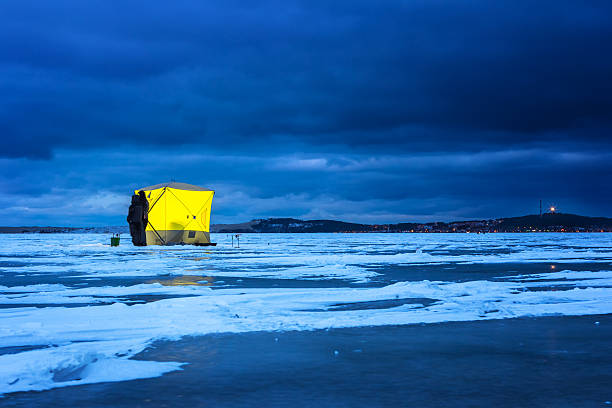 Night ice fishing. Night ice fishing. Yellow fishing shelter on the ice at night,  Nida, Lithuania ice fishing stock pictures, royalty-free photos & images