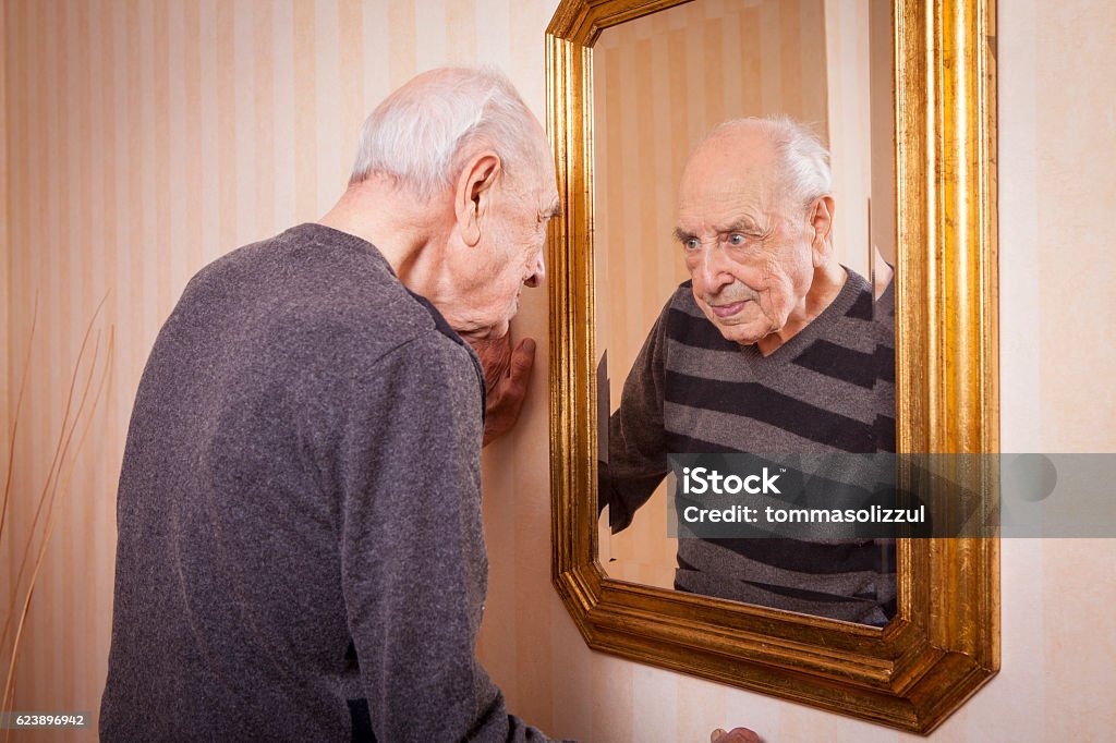 ältester Mann, der sich selbst in den Spiegel schaut - Lizenzfrei Spiegel Stock-Foto