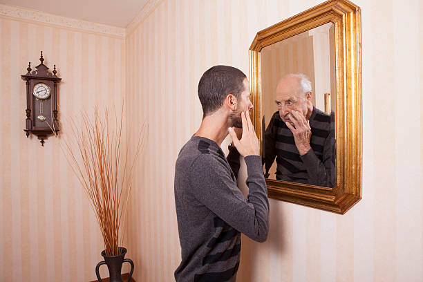 istock young man looking at an older himself in the mirror 623897746