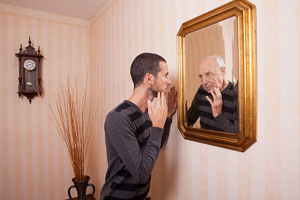 istock young man looking at an older himself in the mirror 623898086