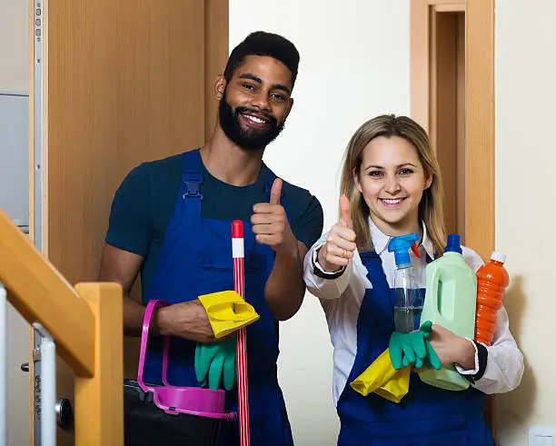 Photo of cleaners in uniform cleaners standing at house doorway