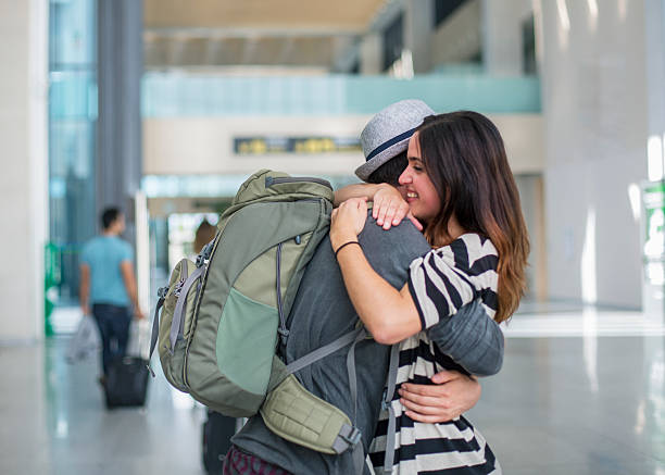 Couple embrace at airport arrival airport terminal arrival meet airport hug stock pictures, royalty-free photos & images