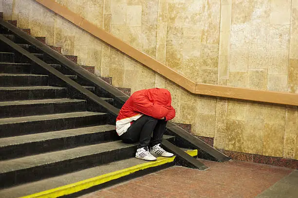 Photo of young homeless man sleeping on the street