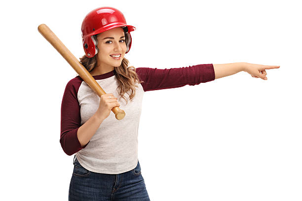 Young woman with a baseball bat and a helmet pointing right isolated on white background