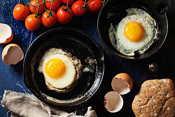 istock Fried eggs in skillets on wooden background 623909326