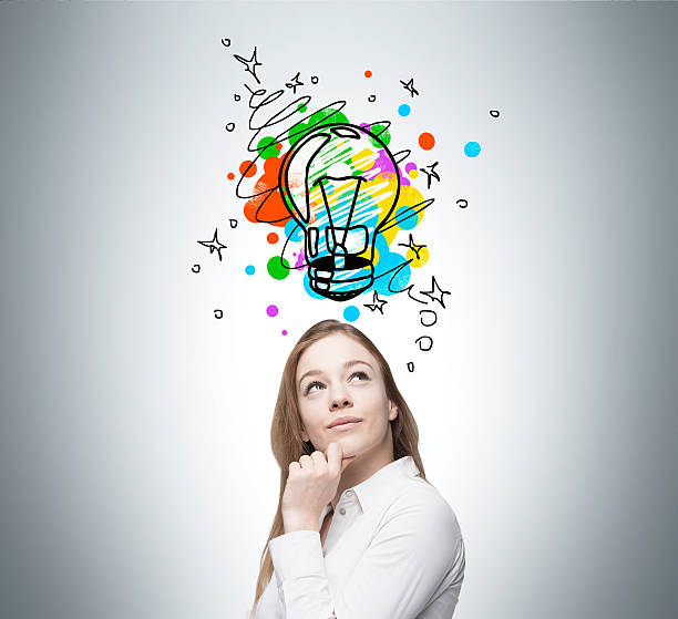 istock Blond woman looking at light bulb on gray wall 623911288