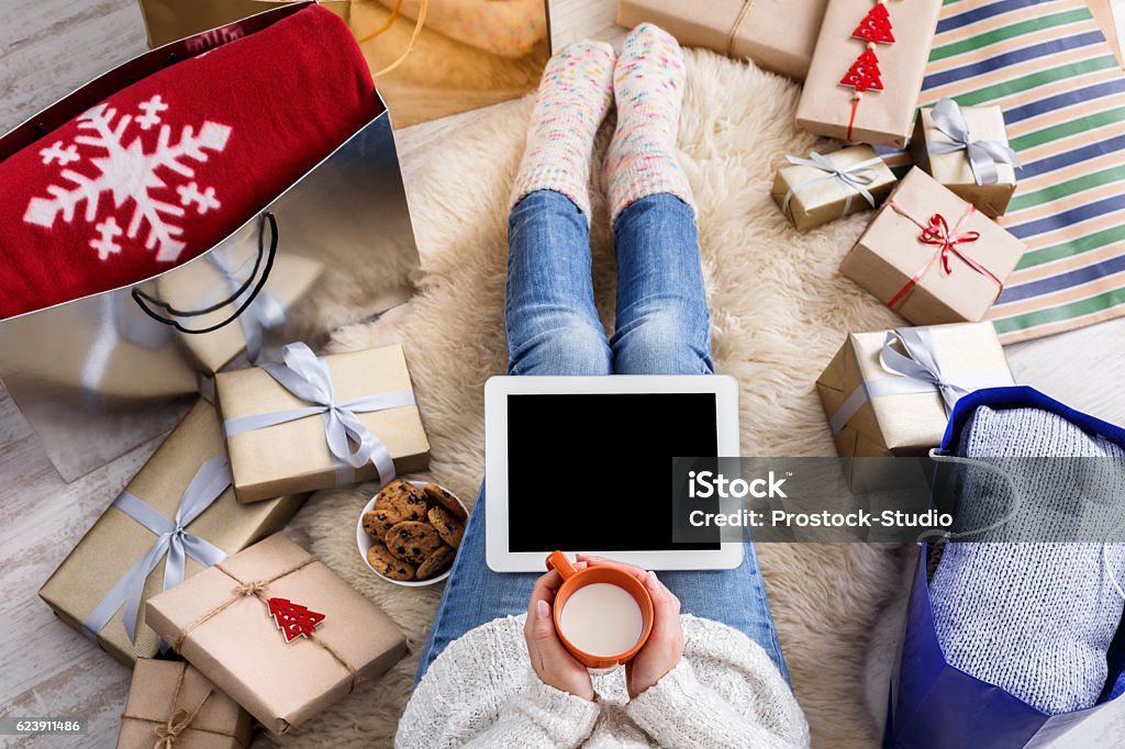 Woman shopping online with a credit card, top view Christmas online shopping top view. Female buyer touch black screen of tablet, copy space. Woman drinks milk, buys presents, prepare to xmas eve, sit near gift boxes and packages. Winter holiday sales Baby Girls Stock Photo