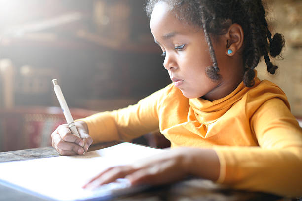 petite fille africaine écrivant. - schoolgirl little girls crayon human face photos et images de collection