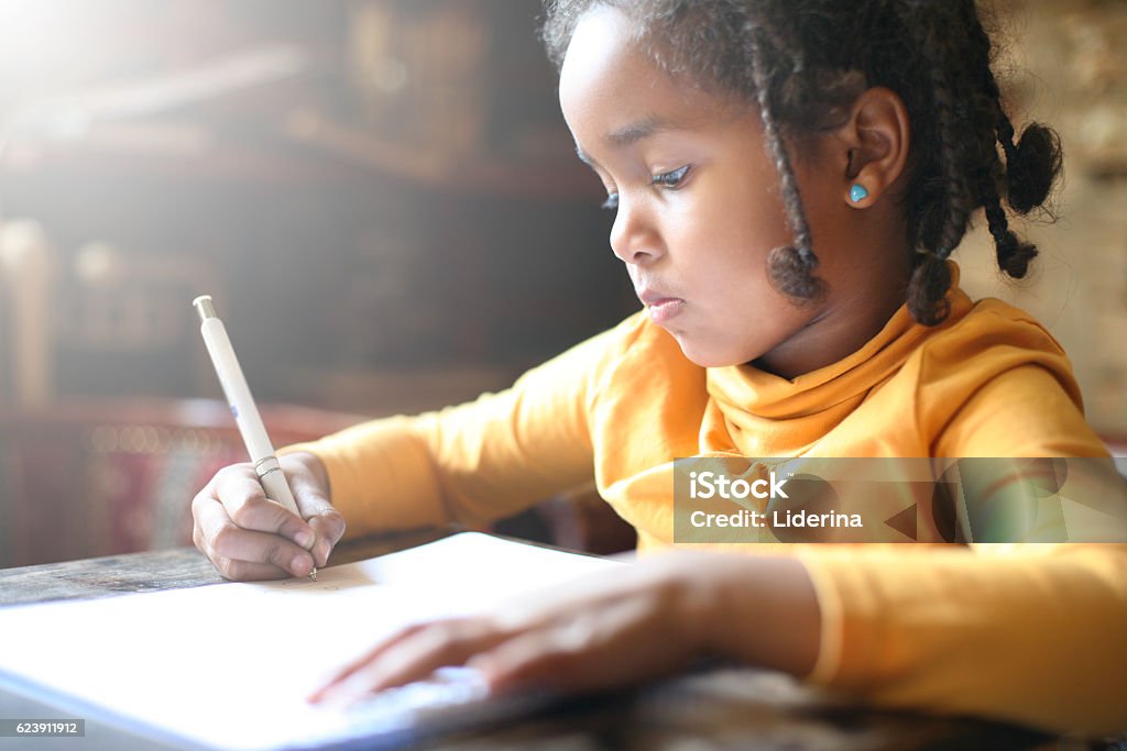 Little African girl writing. School child. African girl writing in notebook. Child Stock Photo