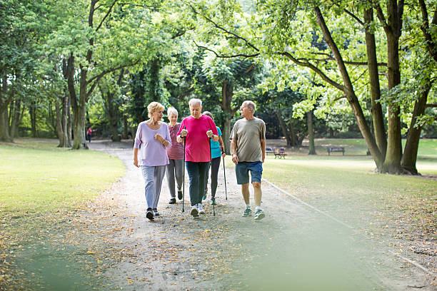grupa seniorów spacerujących po parku - nordic walking zdjęcia i obrazy z banku zdjęć