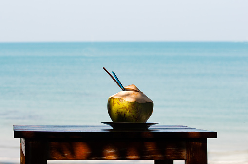 Coconut shake on wooden table with sea in background