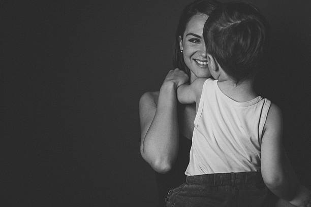 Mother and son studio portrait, isolated on black; celebrating Mother's day 