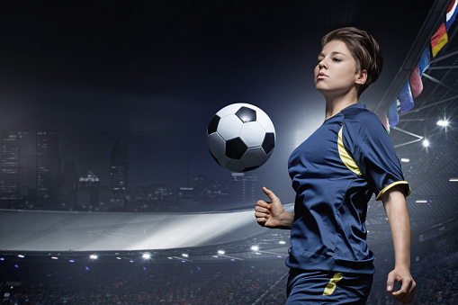 Caucasian young adult female soccer player playing football in stadium