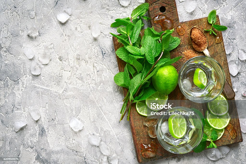 Ingredients for making mojito.Top view. Ingredients for making mojito on a wooden cutting board on grey concrete or stone background.Top view. Mint Julep Stock Photo