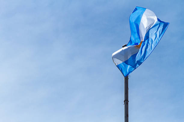 флаг аргентины пылает на фоне голубого неба в буэно�с-айресе - national flag flag global communications sky стоковые фото и изображения