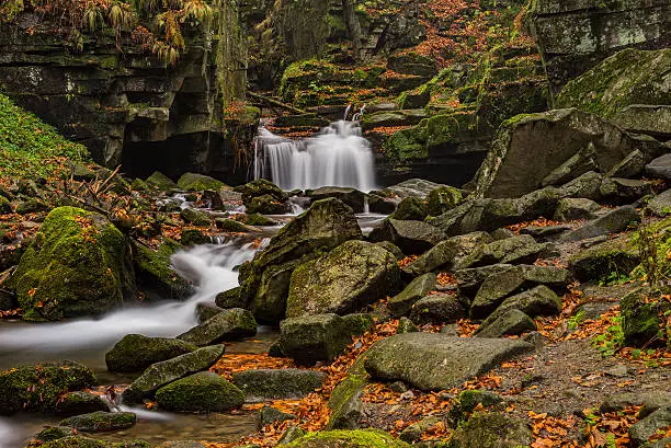 View of autumn stream with waterfalls with stones