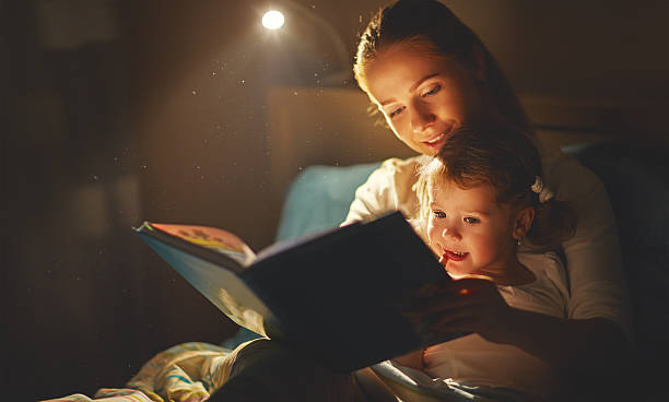 mutter und kind mädchen lesen ein buch im bett - fairy tale stock-fotos und bilder