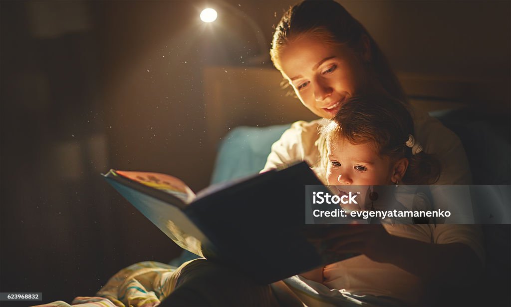 mother and child girl reading a book in bed mother and child girl reading a book in bed before going to sleep Reading Stock Photo