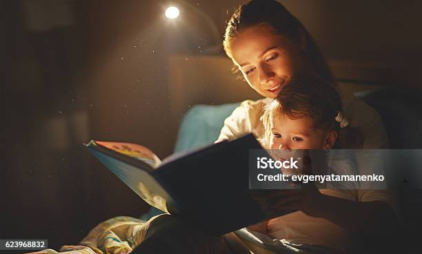 Mother And Child Girl Reading A Book In Bed Stock Photo - Download Image Now - Reading, Child, Mother