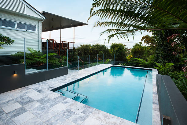 istock Blue water swimming pool with floor tiles under green trees 623982444
